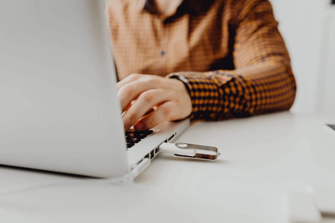 Cloud Storage Compared Drive - Person working on a laptop with a USB flash drive connected