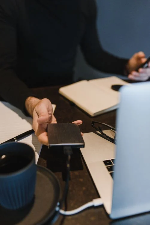 Cloud Storage Compared Drive - Person holding an external hard drive next to a laptop