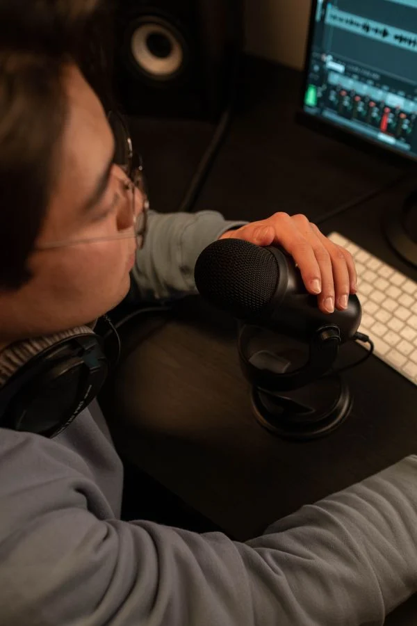 Granola AI Meeting Notes - Person wearing headphones speaking into a microphone at a desk, illustrating local audio capture