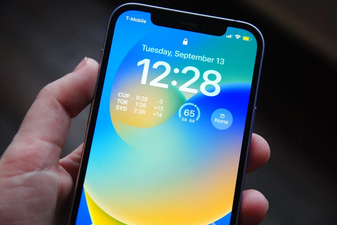 Pexels (photo ID 13628543) — free to use under the Pexels license; photographer name not present in returned metadata. Verified: hand holding an iPhone showing its lock screen (landscape, 1120x750).